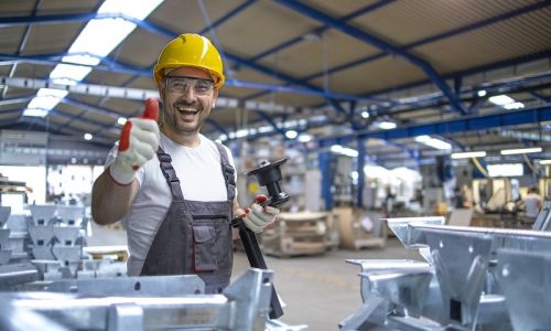 portrait-factory-worker-protective-equipment-holding-thumbs-up-production-hall-min